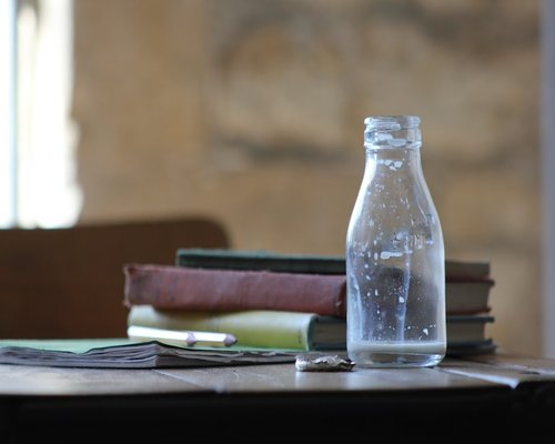 A glass of water next to a notebook on a desk